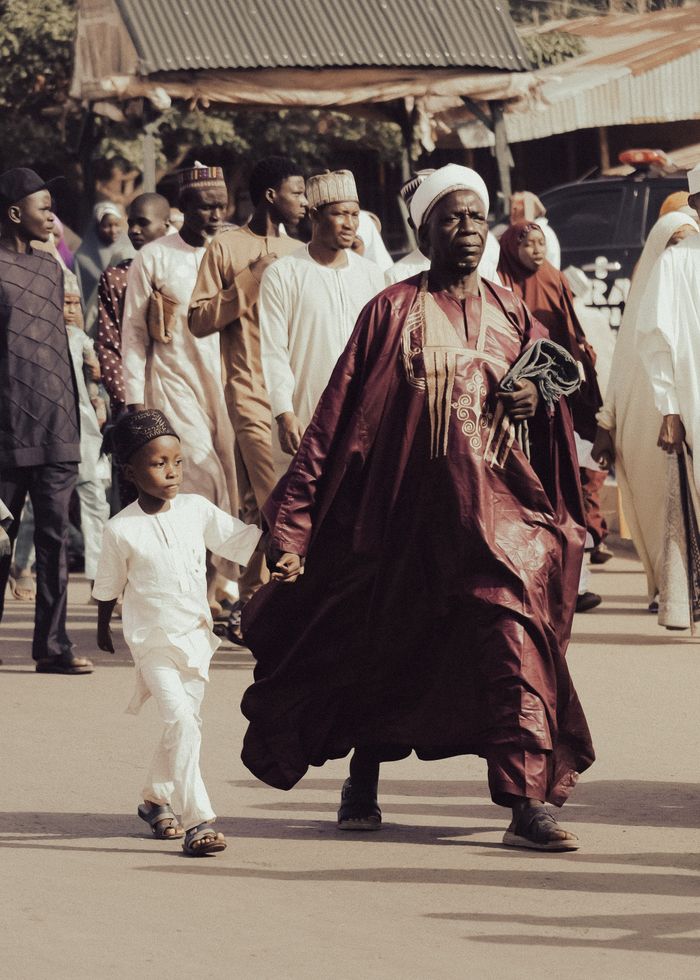 A diverse group in traditional attire parading outdoors, showcasing vibrant cultural heritage.